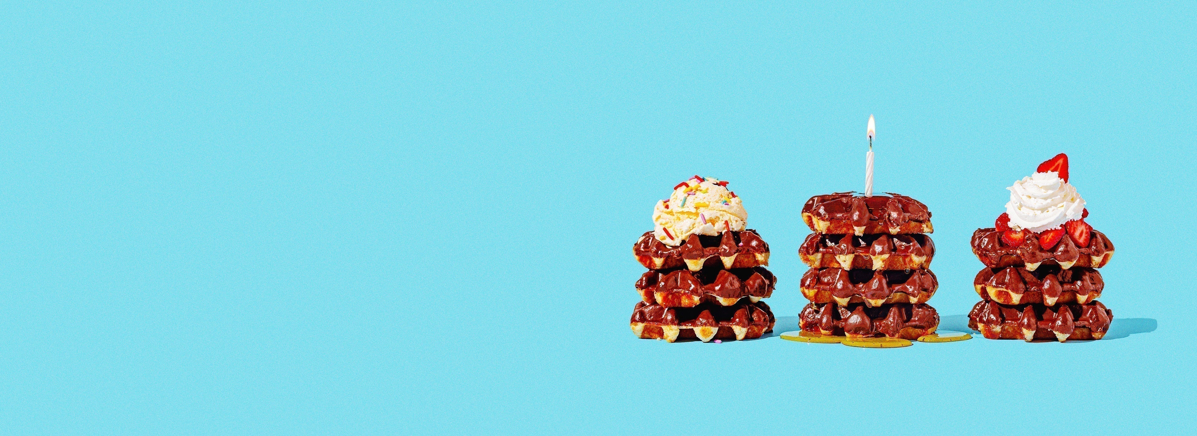 Three stacks of chocolate coated Belgian waffles with different toppings